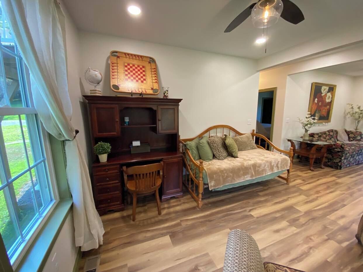 A cozy room with a wooden desk, a comfortable sofa, and a ceiling fan.