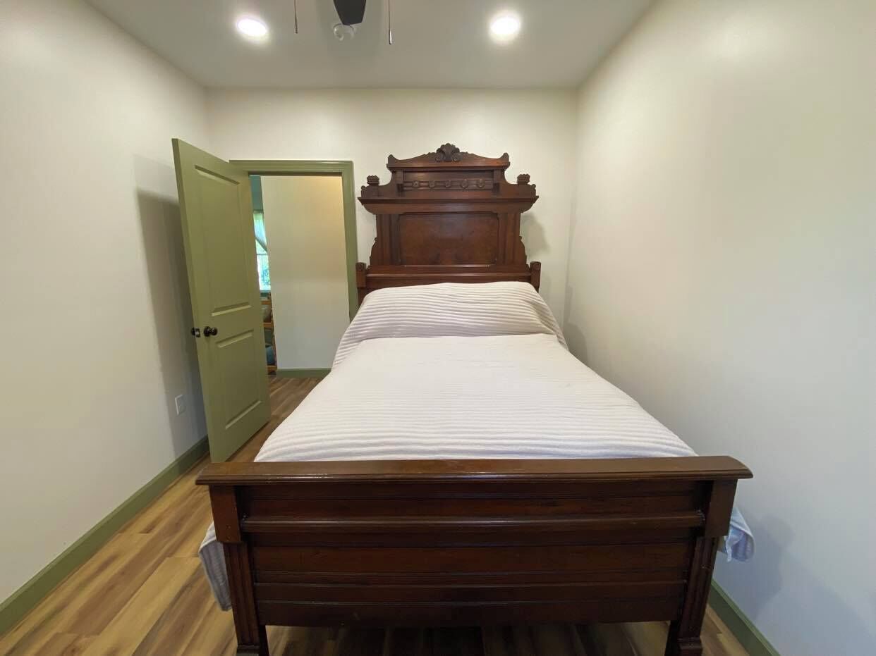 A bedroom with a wooden bed, a door, and a light switch on the wall.