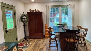 A dining area with a wooden table and chairs, a ceiling fan, and a view of the outside. - Historic Sears & Robuck River Home (Main Level) The Village at Houser's Crossing (Tamaqua)