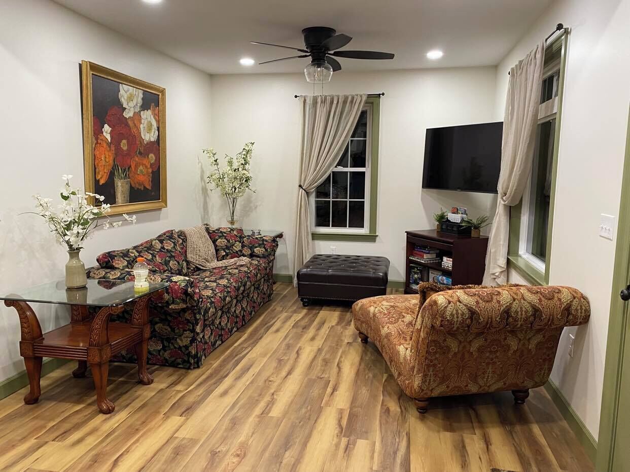 A living room with a sofa, ottoman, coffee table, and a TV.