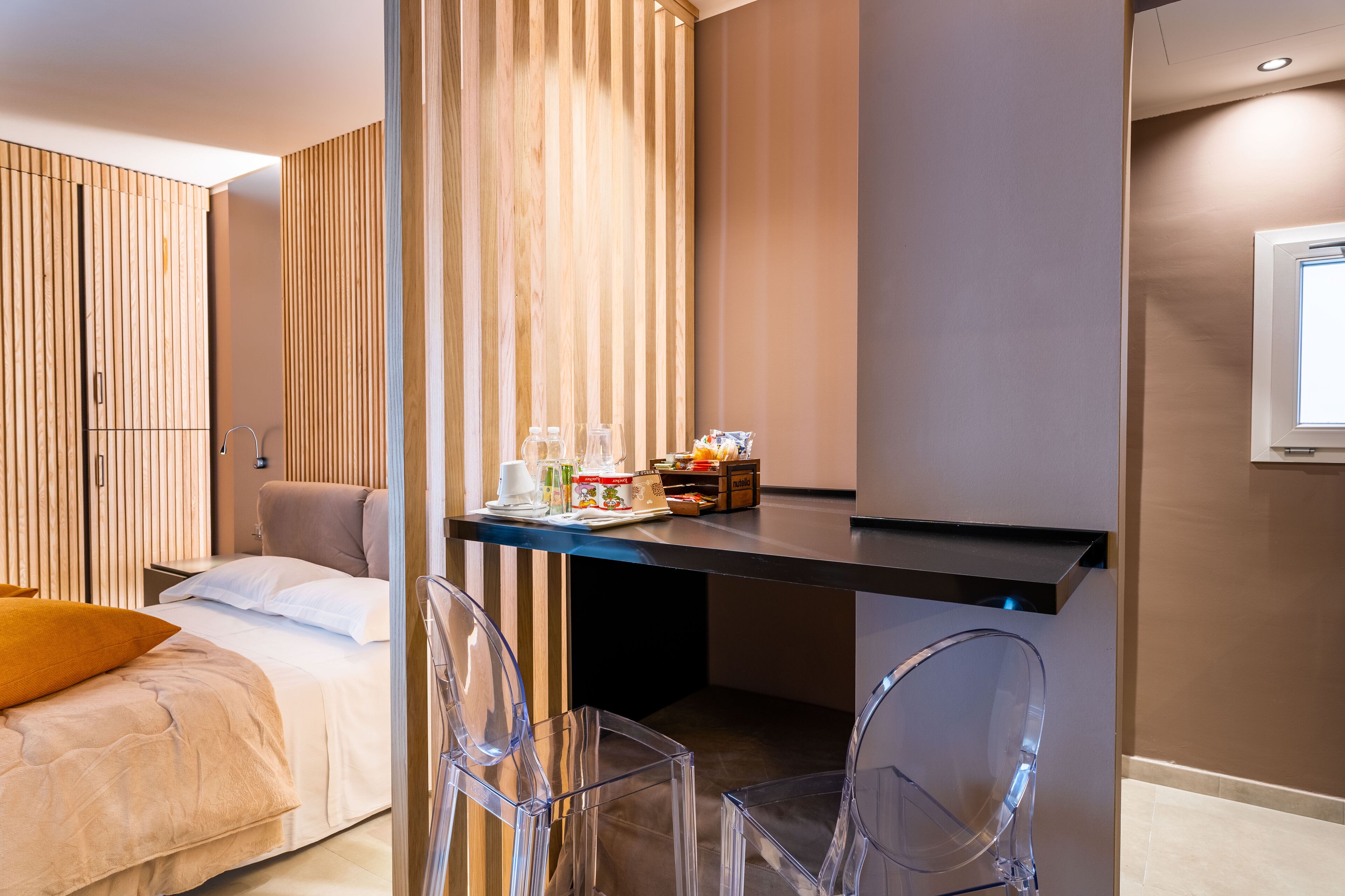 A modern hotel room with a bed, a desk with a computer, and a chair.
