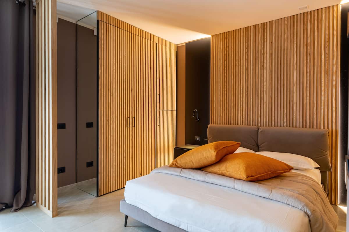 Ein modernes Schlafzimmer mit einem großen Bett, Holzvertäfelung und einem Kleiderschrank.