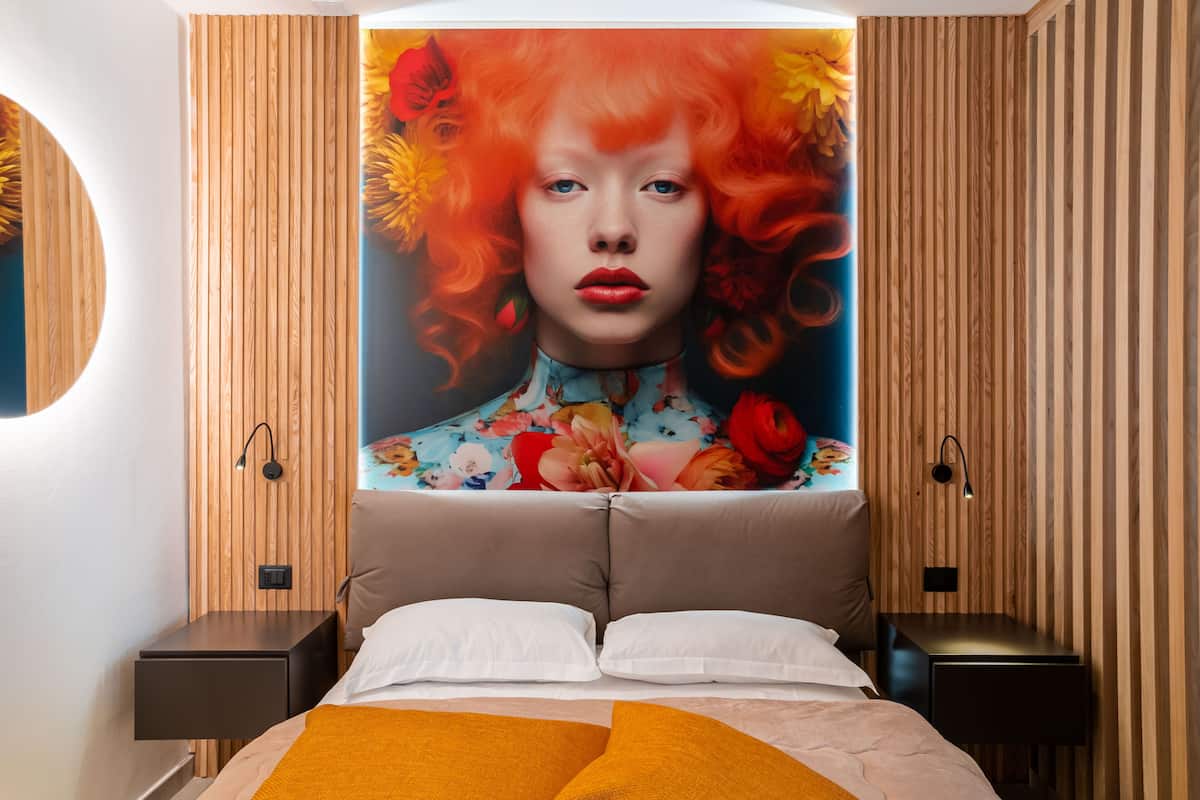 Ein modernes Schlafzimmer mit einem großen Bett, zwei Nachttischen und einer wandmontierten Leuchte.