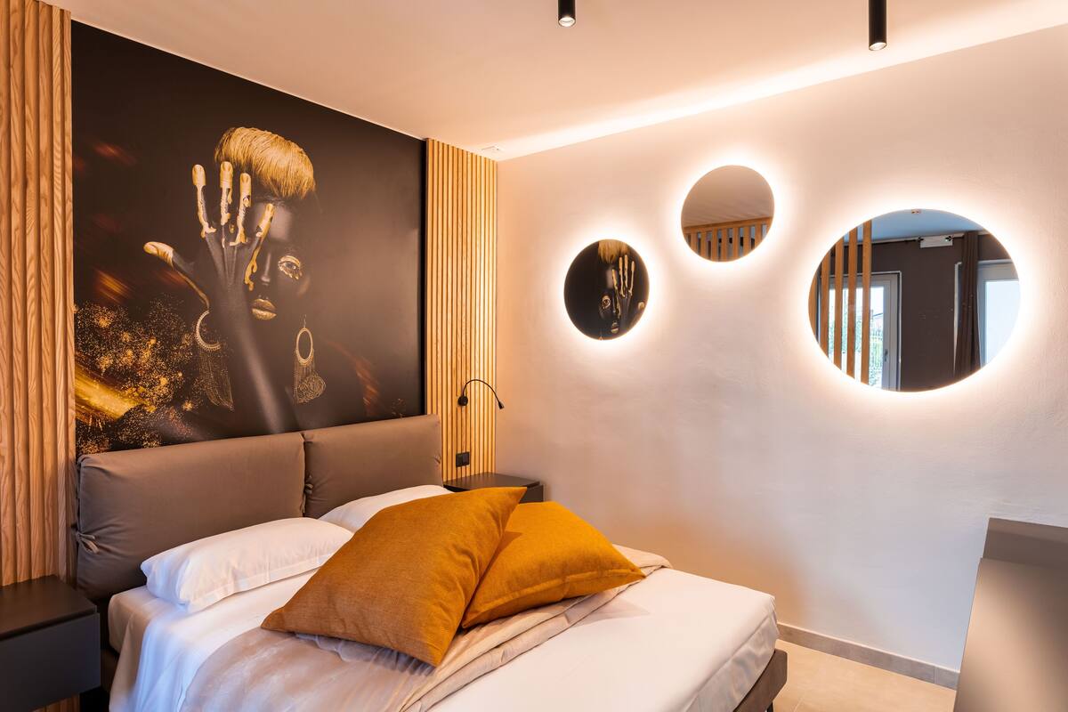 Ein modernes Schlafzimmer mit einem großen Bett, einem Kopfteil mit vertikalen Lamellen und runden Wandspiegeln.