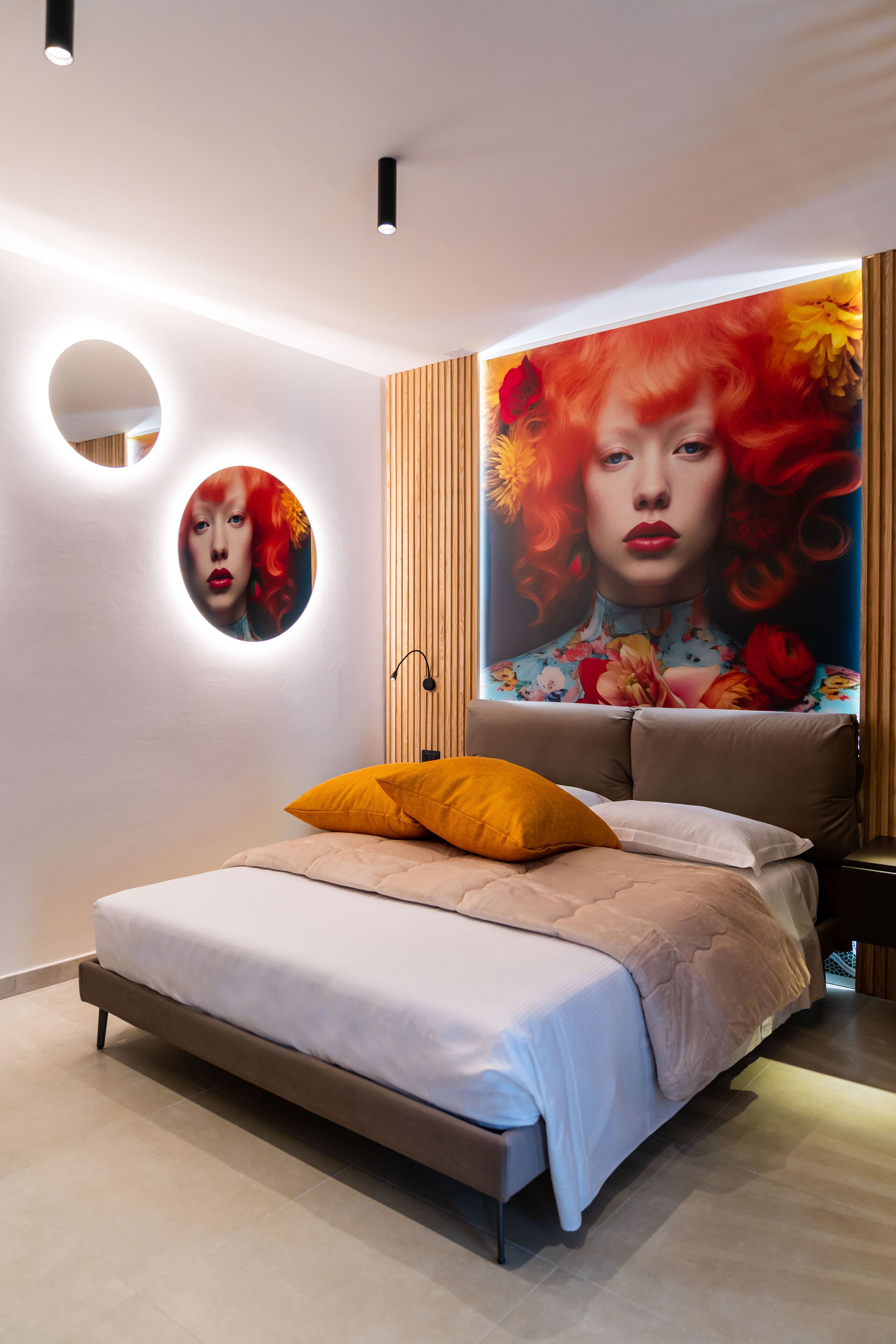 A modern bedroom with a large bed, a round mirror, and a vibrant floral mural on the wall.