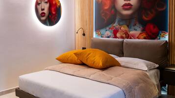 A modern bedroom with a large bed, a round mirror, and a vibrant floral mural on the wall.