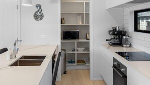 Une cuisine moderne équipée d’un four à micro-ondes, d’une machine à café et d’un four encastrés.