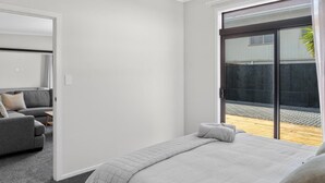 Une chambre moderne avec un lit, un canapé et une porte-fenêtre coulissante donnant sur un balcon.