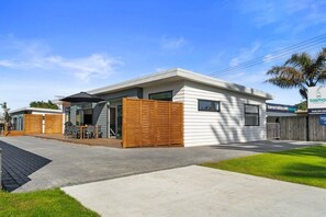 Een modern huis met twee verdiepingen, een terras, een houten omheining en een bordje voor Tasman Holiday Park.