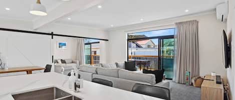 A modern living room with a marble island, grey sofa, and large windows.