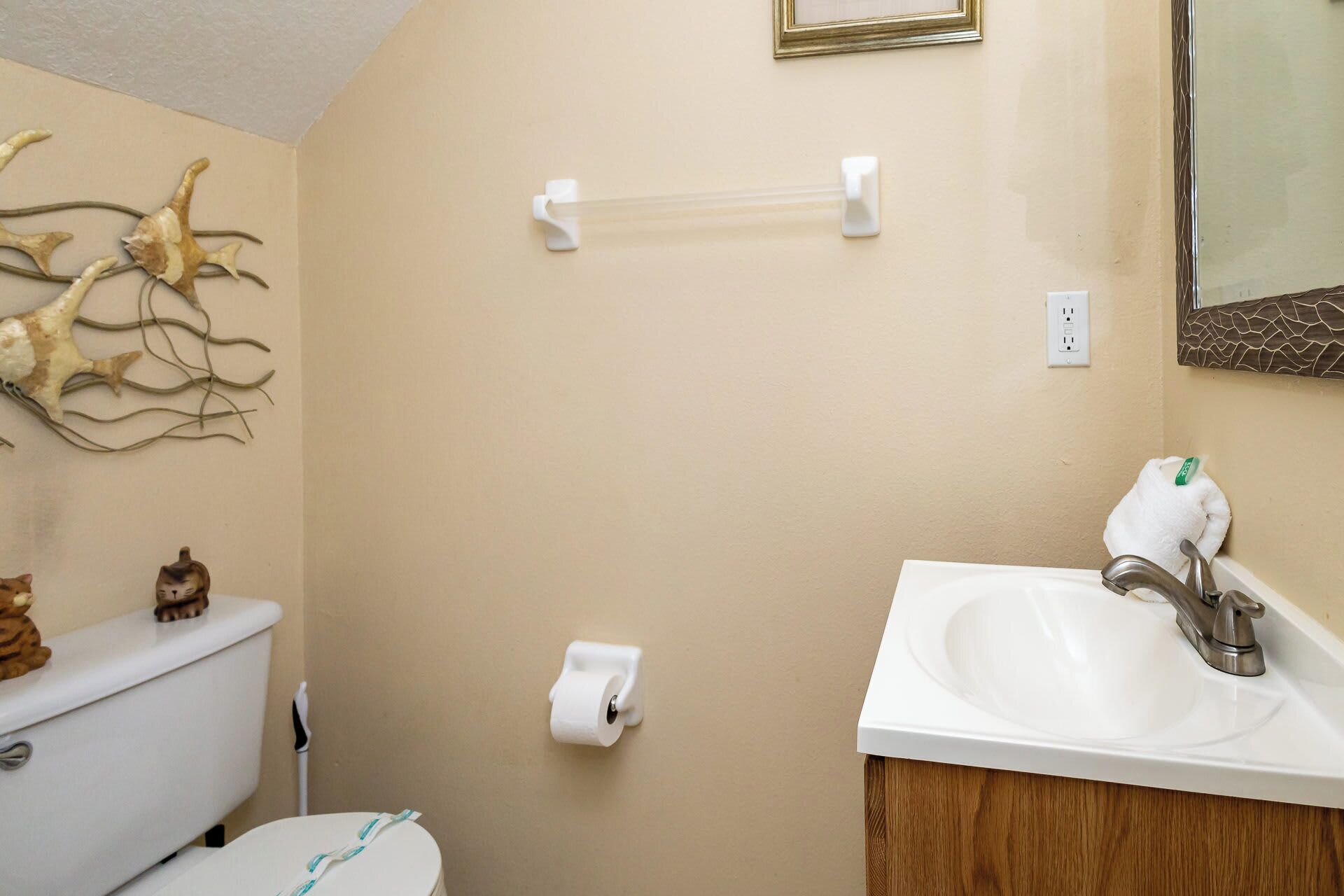 Un baño con inodoro, lavamanos y un adorno en la pared.