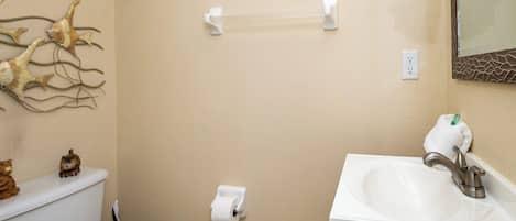 Un baño con inodoro, lavamanos y un adorno en la pared.