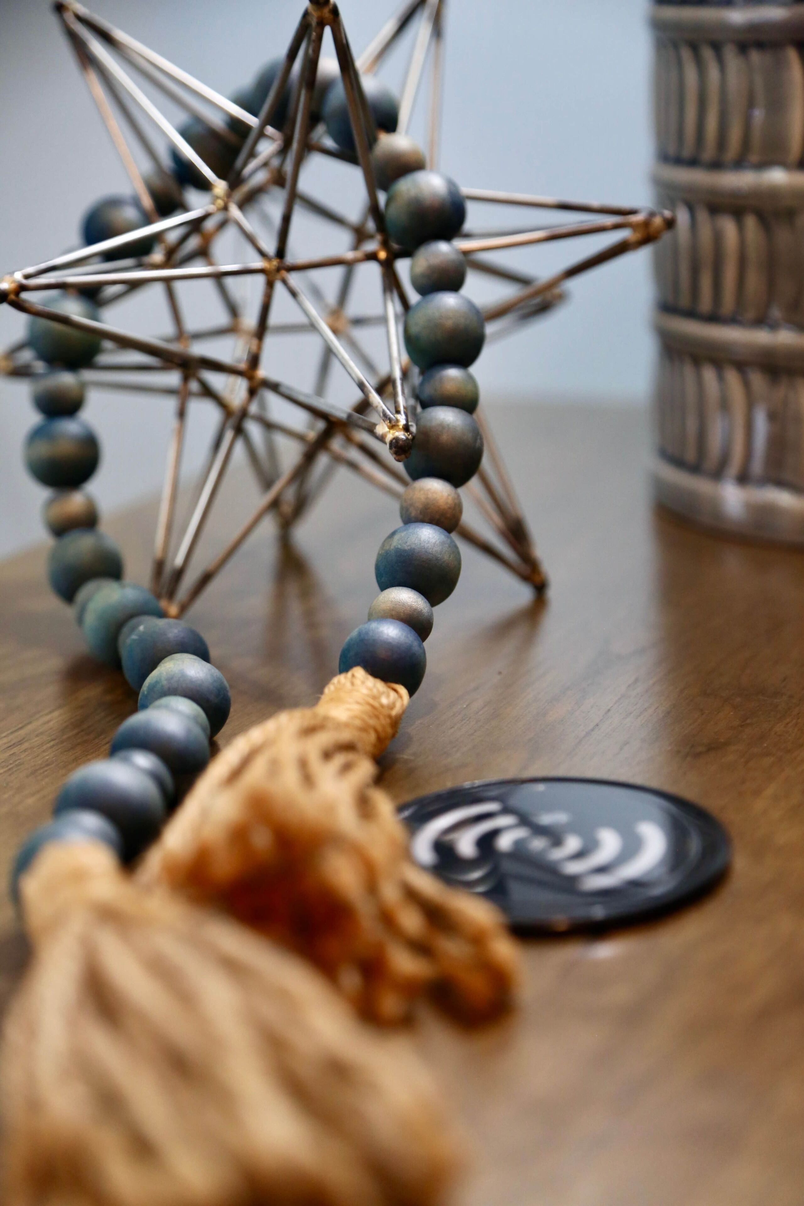 A wooden surface with a star-shaped metal object and a beaded necklace.