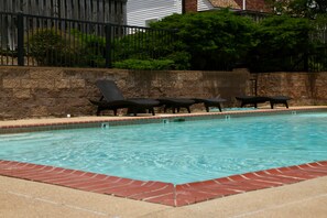 Une piscine avec des chaises longues et un mur en pierre.