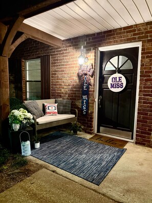 A brick exterior with a bench, a welcome mat, and a door with a sign.