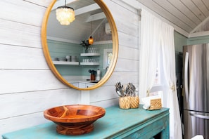 Enjoy a functional kitchen with a rustic touch, featuring a large mirror, wooden bowl, and modern appliances.