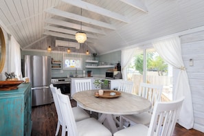 Enjoy cooking and dining in this well-appointed kitchen with a stove, microwave, and refrigerator, surrounded by a dining table and wooden bench.