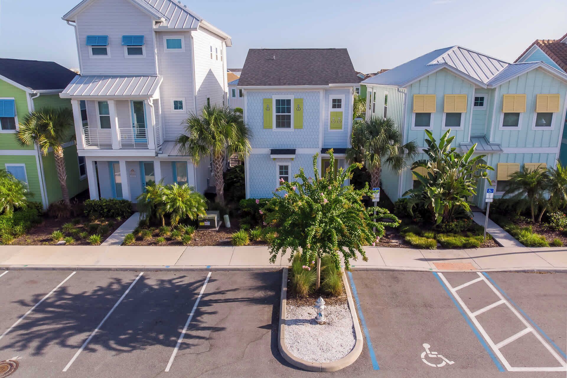 A row of colorful houses with a parking lot in the foreground.