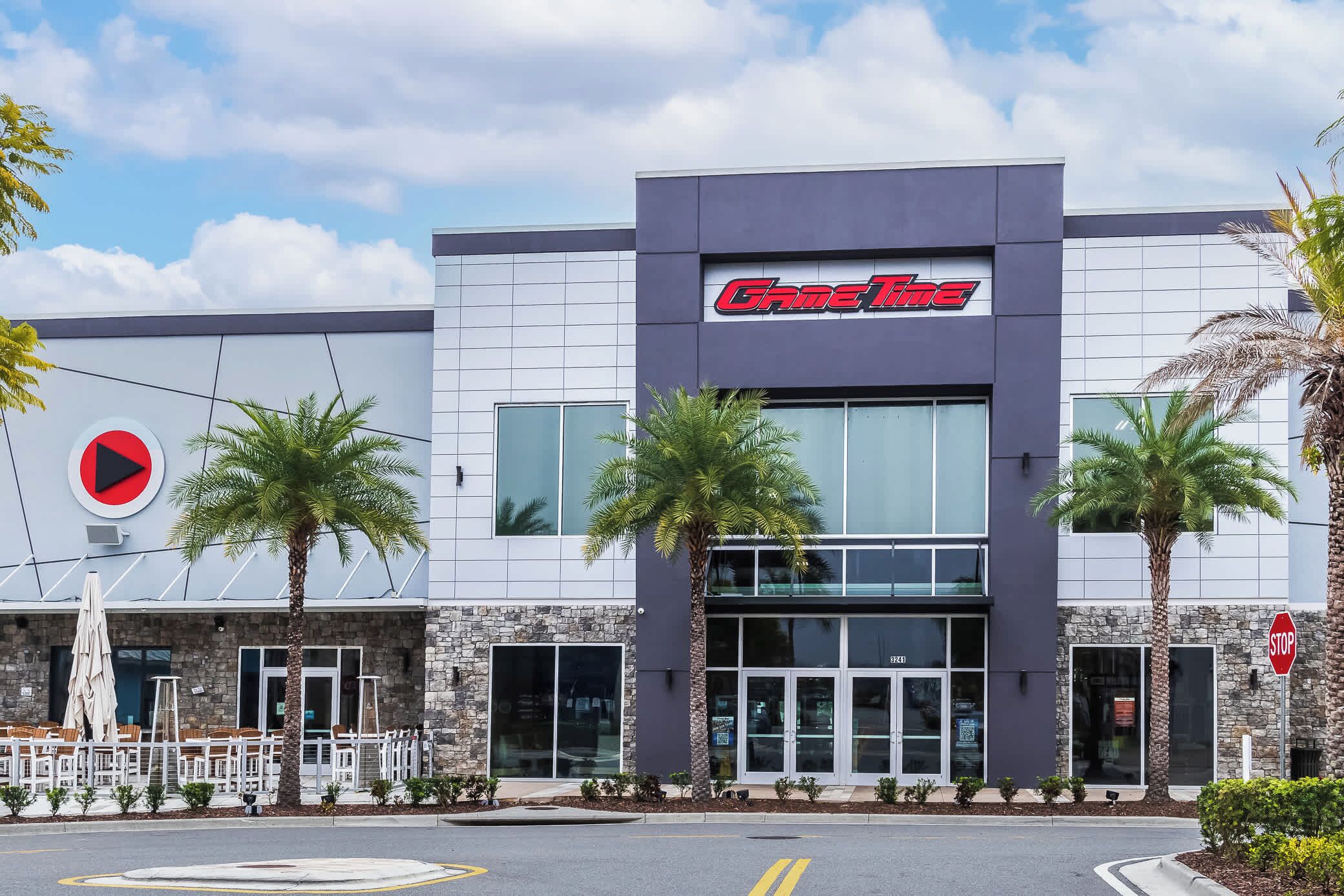 A building with a 'GameTime' sign, palm trees, and a stop sign.