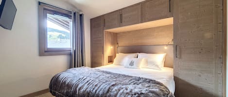 A bedroom with a bed, a window, and wooden paneling.