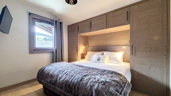A bedroom with a bed, a window, and wooden paneling.