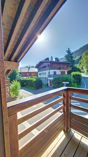 A wooden balcony with a view of a mountain and buildings.