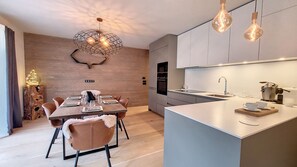 A modern kitchen with a central island, built-in appliances, and pendant lighting.