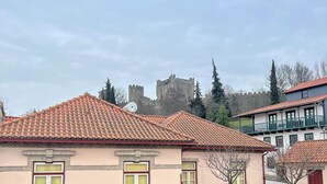 Un edificio tradicional con tejado de baldosas y una torre de piedra al fondo.