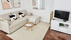 Un salón moderno con un sofá color beige, una mesa de centro, un televisor y obras de arte en las paredes.