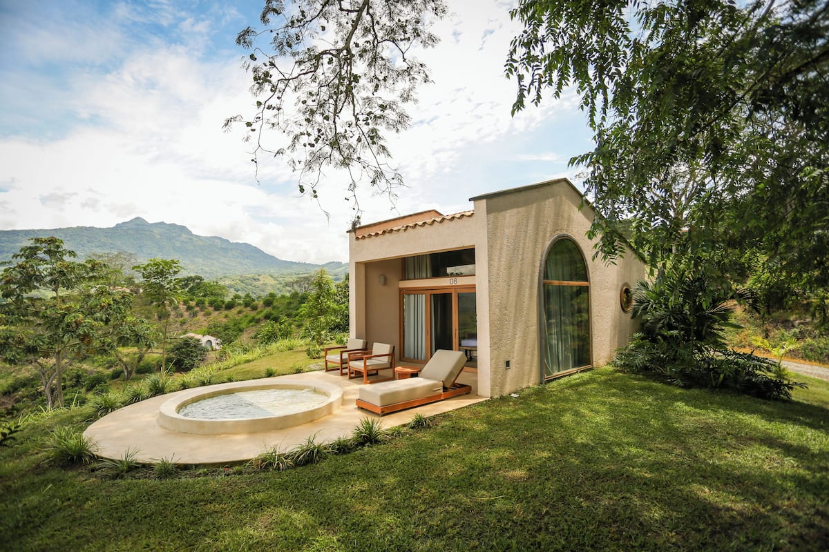 A modern house with a patio, a swimming pool, and a view of mountains.