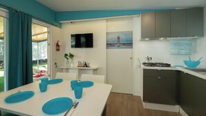 Eine moderne Küche mit grauen Schränken, einer weißen Arbeitsplatte und einer blauen Schüssel. Ein Esstisch mit blauen Tellern und Besteck ist ebenfalls vorhanden.