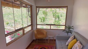 A room with a grey sofa, a yellow chair, and a patterned rug. - Quinta San Martin (Ollantaytambo)