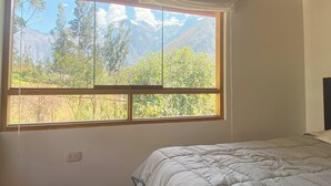 A bedroom with a large window offering a mountain view. - Quinta San Martin (Ollantaytambo)