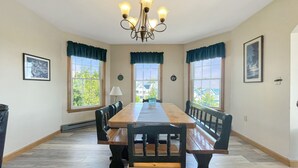 A dining room with a long wooden table, black upholstered benches, and a chandelier. - High View at Short Sands - Beautiful condo at Short Sands Beach (York)