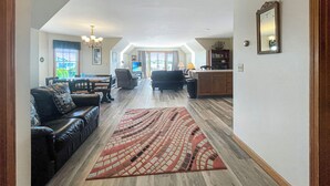 A spacious living area with a sofa, a dining table, and a kitchen in the background. - High View at Short Sands - Beautiful condo at Short Sands Beach (York)