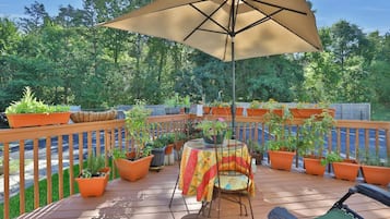Una terraza con mesa y sillas, rodeada de plantas en macetas y una valla de madera.