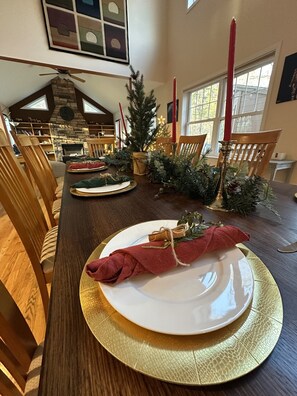 A dining area with a long table set for a meal, surrounded by chairs.