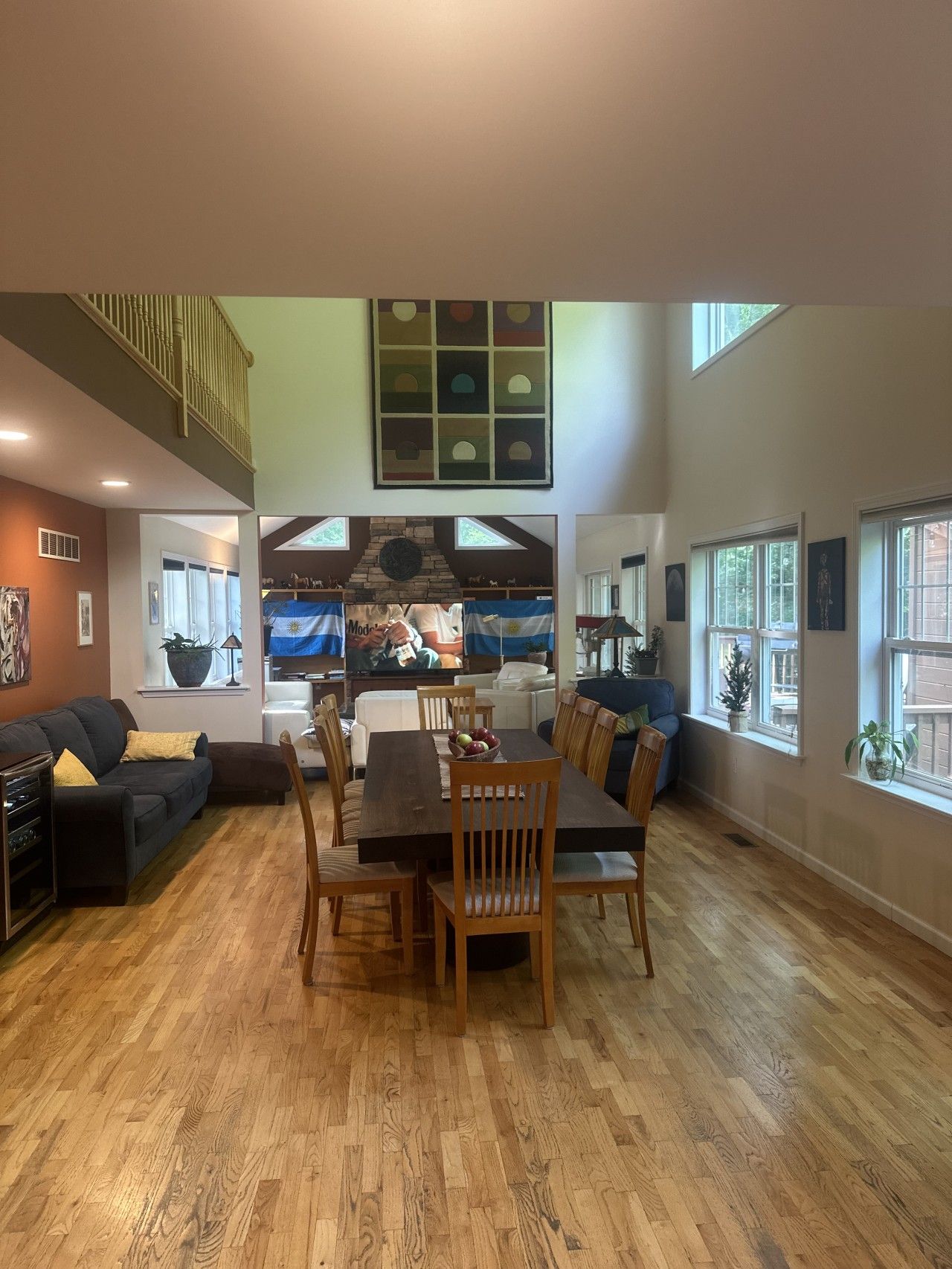 A spacious living area with a dining table, wooden chairs, a sofa, and a television.