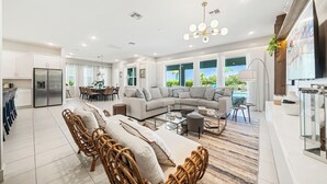 A spacious living area with a large sofa, dining table, and wicker chairs. - 5BR, Reunion Resort, villa, games room (Kissimmee)