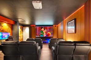 Un home theater con poltrone in pelle nera reclinabili, un grande schermo e pannelli in legno.