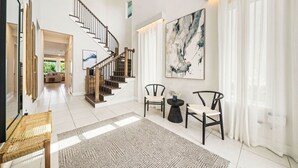 A spacious living area with a staircase, modern furniture, and artwork. - 5BR, Reunion Resort, villa, games room (Kissimmee)