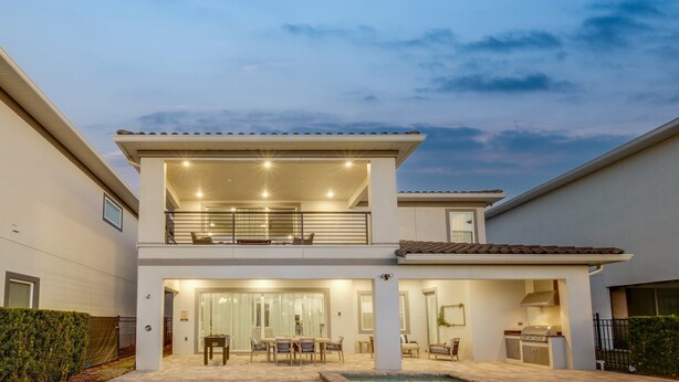 A two-story house with a balcony, a patio with outdoor furniture, and a swimming pool. - 5BR, Reunion Resort, villa, games room (Kissimmee)