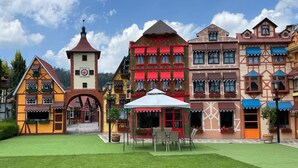 A traditional European-style building with a central tower, multiple windows, and a small outdoor seating area with tables and chairs. - Villa Clauss (Tlalpujahua)