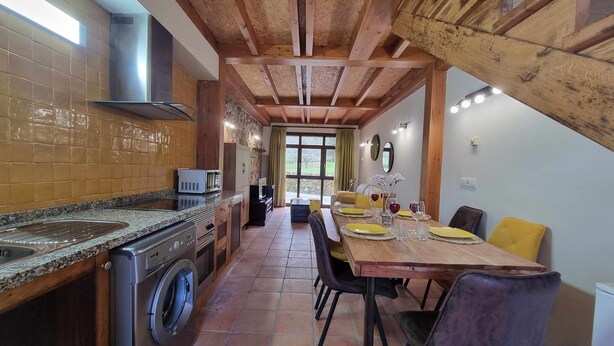 A kitchen with a washing machine, a microwave, and a dining area with a table set for two. - Los Gemelos Vacation Home (San Roque Del Acebal)