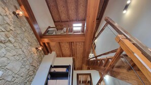 A multi-level wooden interior with stone walls and a staircase. - Los Gemelos Vacation Home (San Roque Del Acebal)
