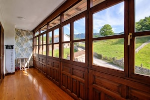 Un corridoio con rivestimenti in legno e ampie finestre che si affacciano su un paesaggio verde e degli edifici.