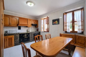 Una cucina con mobili in legno, un piano cottura nero e un tavolo da pranzo con sedie.
