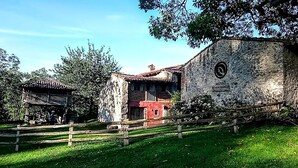 Un bâtiment rustique en pierre, avec une façade rouge et une clôture en bois à l’avant.