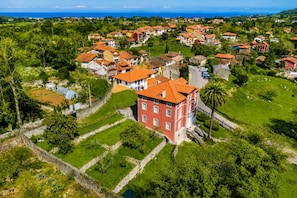 Vista aérea de una zona residencial con casas, espacios verdes y un edificio rojo destacado con tejado rojo.