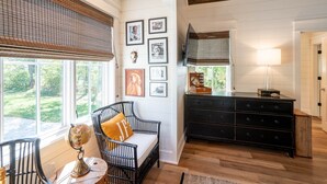 Une pièce comprenant un fauteuil en osier noir, un globe terrestre posé sur un socle en bois, une commode noire et des tableaux encadrés accrochés au mur.
